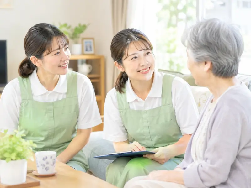 先輩と新人が、利用者さんの家で話を聞いている様子